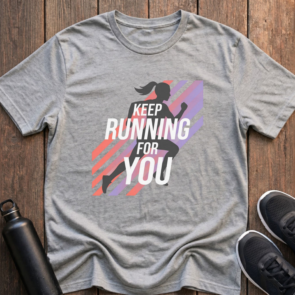 Gray t-shirt with running-themed design on a wooden surface with sneakers and a water bottle.